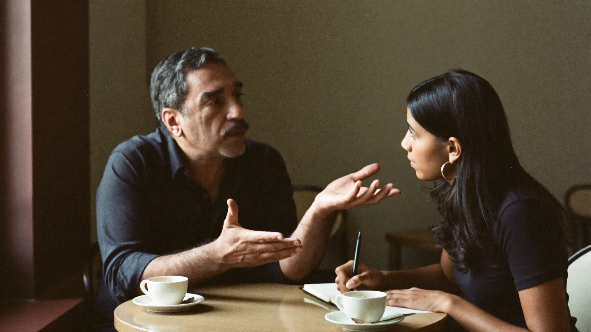 An experienced mentor advising a younger professional in a café