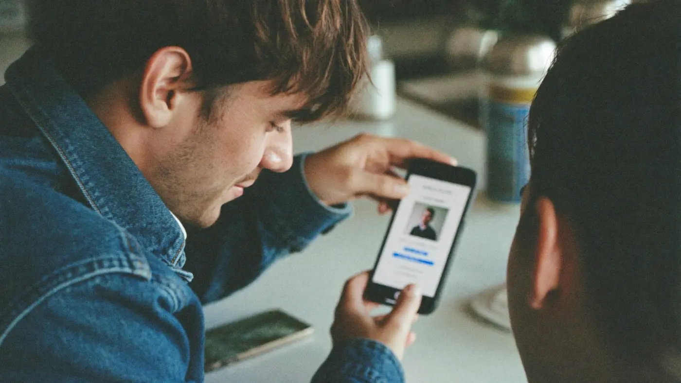 Two friends looking at a job listing on a phone
